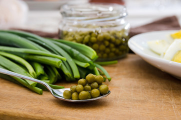 green onions, chopped eggs on a plate and canned peas on a wooden board. The concept of cooking spring salad.