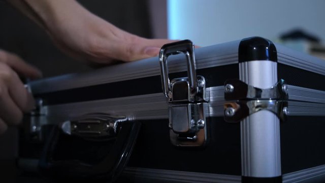 Secret suitcase with light. Concept. Close-up of woman opening mysterious black suitcase emitting neon light. Woman hides something unusual in mysterious suitcase