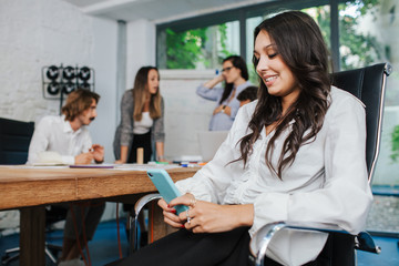 Young businesswoman uses smartphone during a break from the business meeting of her start-up - Millennial in a professional refresher lesson relaxes with her device