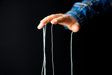 puppeteer's hand with ropes on fingers control the people mind concept