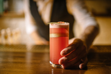 barmen holding on his hand rhubarb cocktail in a highball glass