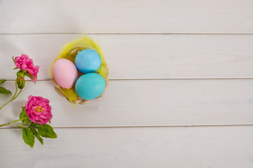 Easter card background. Easter multi-colored eggs on a white wooden background with a flowers with copy space. Happy easter. Flat lay.