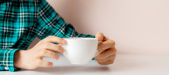 person sitting at the table and drink cup of tea at home in the evening  wide web banner