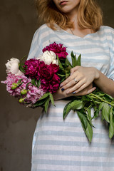 girl in a striped dress with a bouquet of peonies