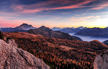 Fantastic View on mountains valley during sunset . Stunning nature landscape with colorful sky over the Autumn forest in Dolomites Alps. Amazing nature landscape with fog.