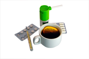 White cup of hot tea with lemon, medical thermometer, blisters with medicines isolate on a white background close-up.