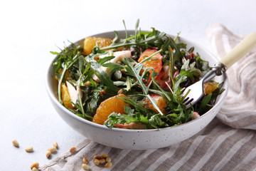 Healthy food. Fresh salad with arugula, mozzarella, baked beetroot, oranges and pine nuts in the bowl with fork. Background image, copy space