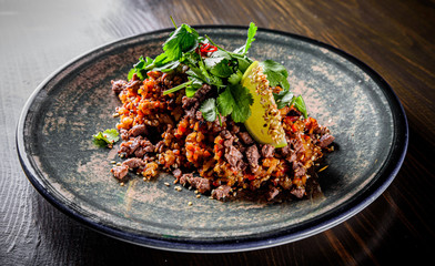 Fried rice with beef meat and vegetables in plate on wooden table background