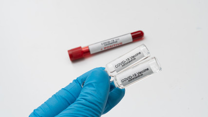Obraz premium Doctor holds COVID 19 Coronavirus vaccine in his hand, infected blood sample in the sample tube, Vaccine and syringe injection It use for prevention, immunization and treatment from COVID-19