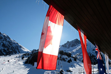 the national flag of Canada hangs against the background of other flags in the mountainous area