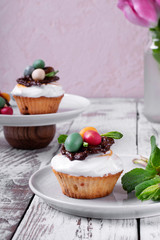 Easter cupcake topped with multicolored marzipan eggs, chocolate nest and marshmallow cream