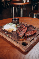 juicy meat steaks with potatoes and sauce on a wooden tray
