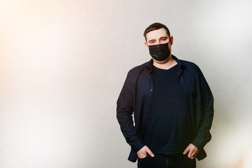 Obraz premium man in black shirt and black hospital mask on gray wall background