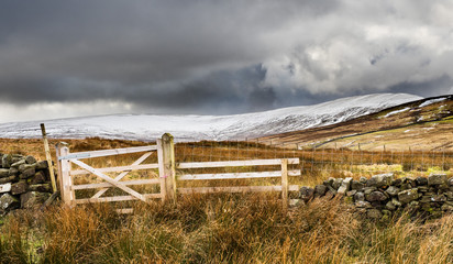 Fototapeta premium Little Whernside mountain in snow from a wooden fence. Scar House. Nidderdale