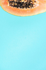 Halved papaya on blue background. Top view. Copy space. Summer time. Tropical travel, exotic fruit. Vegan and vegetarian concept