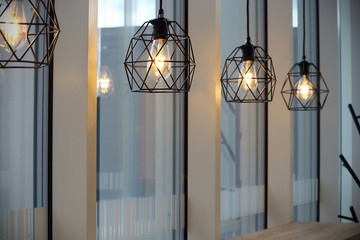 Modern cafe black metal carcass lamps near windows