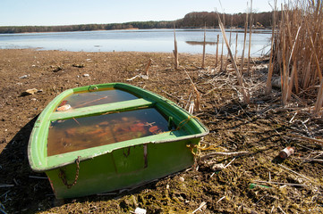 Little green fishing boat on the dried lake. Global warming and drought problem