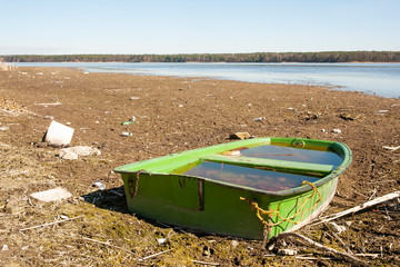 Little green fishing boat on the dried lake. Global warming and drought problem