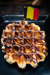 Belgian waffle with chocholate cream. Selective focus, narrow depth of field. Belgian flag in it