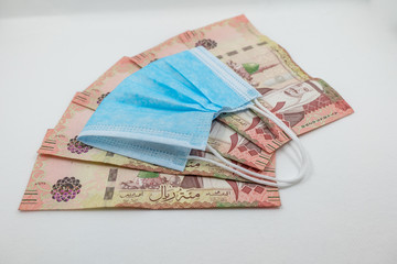 Saudi Arabian 100 Riyal bank note with surgical protective face mask