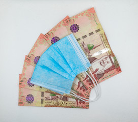 Saudi Arabian 100 Riyal bank note with surgical protective face mask