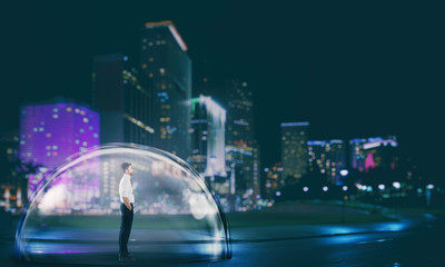 Businessman safely inside a shield dome in the city at night. Protection and safety concept