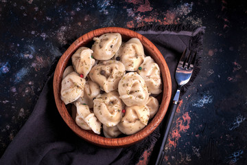 Fototapeta premium Meat dumplings on a wooden plate. Russian pelmeni. Ravioli with meat on a dark background
