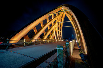 Wooden traffic bridge in the evening with illuminated curved lines and high-up perspective
