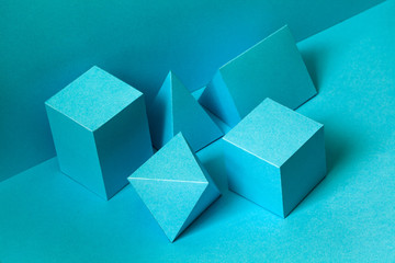 Fototapeta na wymiar Abstract geometrical figures still life composition. Three-dimensional prism pyramid rectangular cube objects on turquoise background. Platonic solids figures, selective focus.