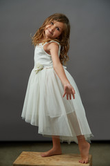 A young girl on gray background doing a dance move