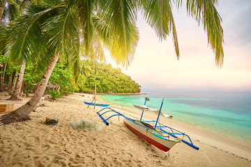 Fisher boat lying peaceful under palm trees at the beach of 