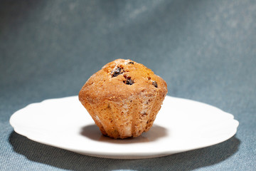 cupcake with raisin sprinkles on a white plate close-up.