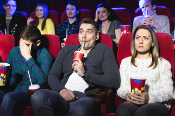 Young scared couple at the cinema watching an horror movie
