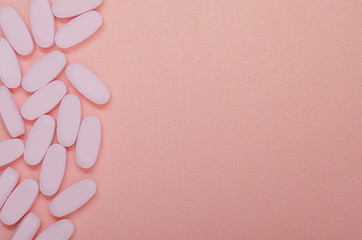 Fototapeta na wymiar Pink pills on a pink background. Vitamins for women.