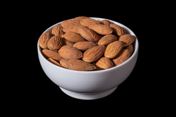 Peeled almonds in a white bowl, isolated on a black background. Image