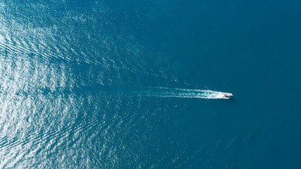 Motor boat sailing in the mediterranean Sea, under the sun, leaving a wake behind. Perfect view for leisure in holidays and travels all over the world - aerial view with a drone - 331285900