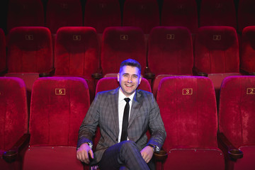 Portrait of a young handsome man alone in a movie theater in a business suit - Powered by Adobe