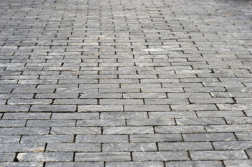 The sidewalk is made of rectangular gray granite bricks . Background