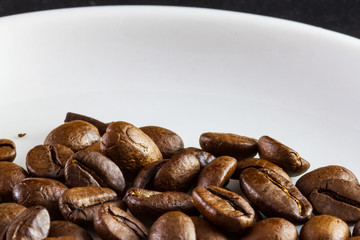 Macro of coffee beans in a white coffee cup