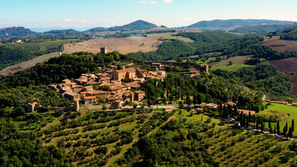 Fototapeta na wymiar An Italian village with green meadows all over the village. Aerial view with a drone of the beautiful and old village of Monticchiello in Tuscany, Italy