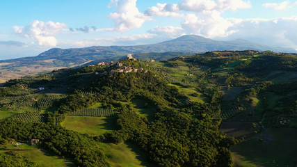 Naklejka premium Dron latający nad wspaniałą autentyczną włoską wioską i zielonymi łąkami. Widok z lotu ptaka na piękną starą wioskę Rocca d'orcia Toskania, Włochy