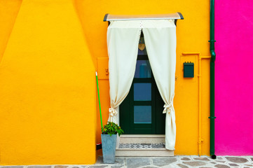 Colorful architecture in Burano island, Venice, Italy. Yellow facade of the house with door.