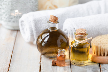 Concept of natural organic oil in cosmetology. Moisturizing skin care and aromatherapy. Gentle body treatment. Atmosphere of harmony relax. Wooden background, white towel, brush. Copy space for text