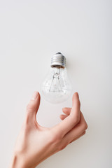 Female hand near the top of an incandescent light bulb upside-down