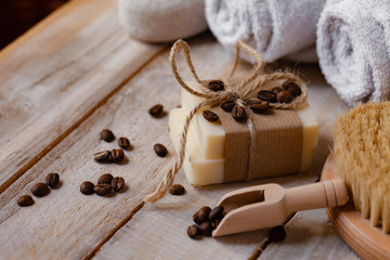 Concept of home natural organic skin care. Handmade soap bars with coffee used as gentle scrub. Brush to increase anti-cellulite effect. Relax pleasant treatement. Wooden background close up