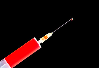 Virus vaccine research background. Syringe isolated on black. Blood test clinic. Red drop at the top of the metal needle. Empty copy space Covid-19 epidemic isolated object for graphic design.