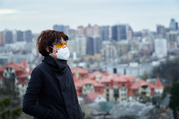 Young fashion styled woman with respirator looking at big city view. Pandemic coronavirus theme