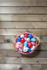 Painted Easter eggs in basket on wooden table