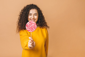 Surprised curly girl eating lollipop. Beauty Model woman holding pink sweet colorful lollipop...