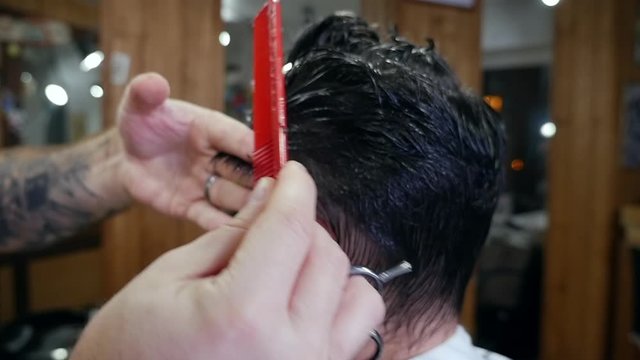 Attractive male is getting a modern haircut in barber shop.